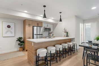 A modern kitchen with white countertops and stools.